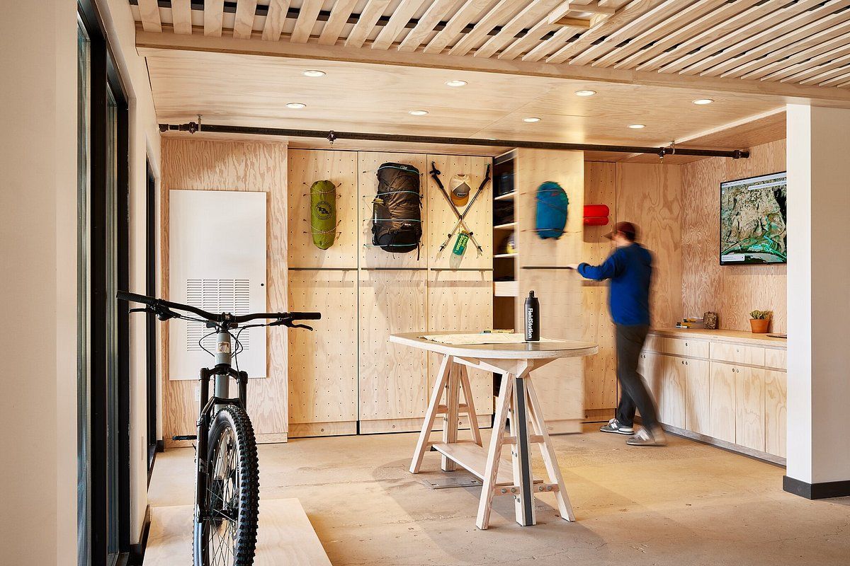 Bike in modern workshop; person in blue and red cap works near wall-mounted skateboards and tools.