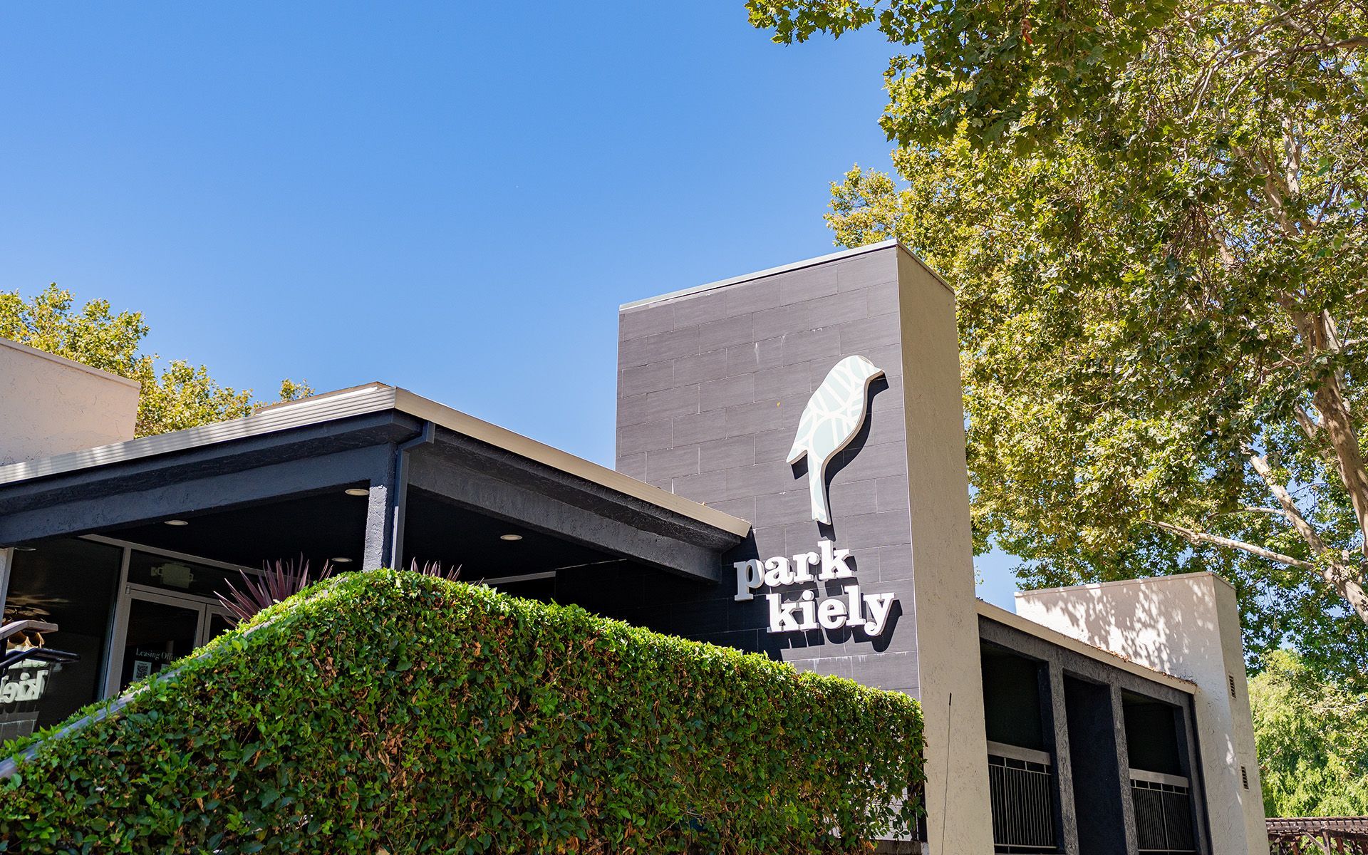Park Kelly sign on a modern building, with green hedges and a clear blue sky
