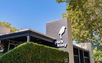Park Kelly sign on a modern building beside trees under a blue sky