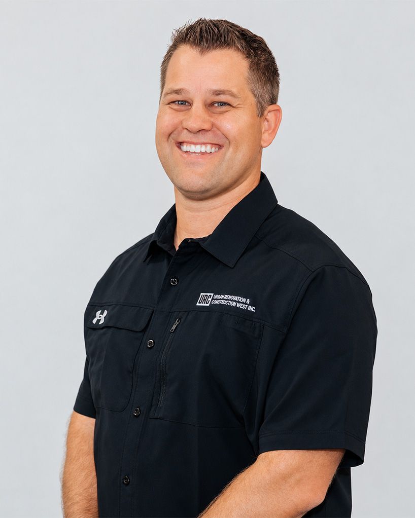Man standing against a plain background, wearing a black button-up shirt and jeans.