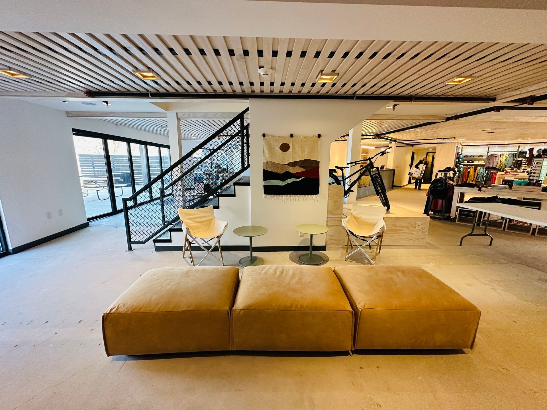 A large room with a couch , chairs , tables and stairs.