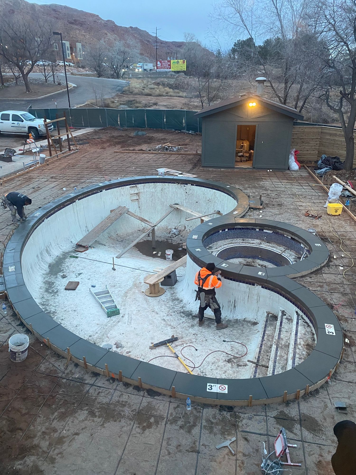 A large swimming pool is being built in the middle of a dirt field.