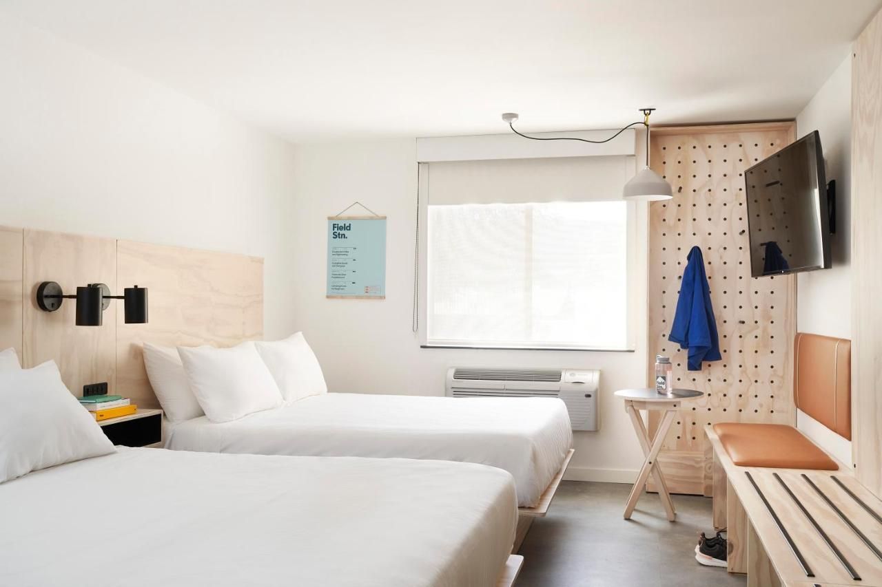 A hotel room with two beds , a table and a television.