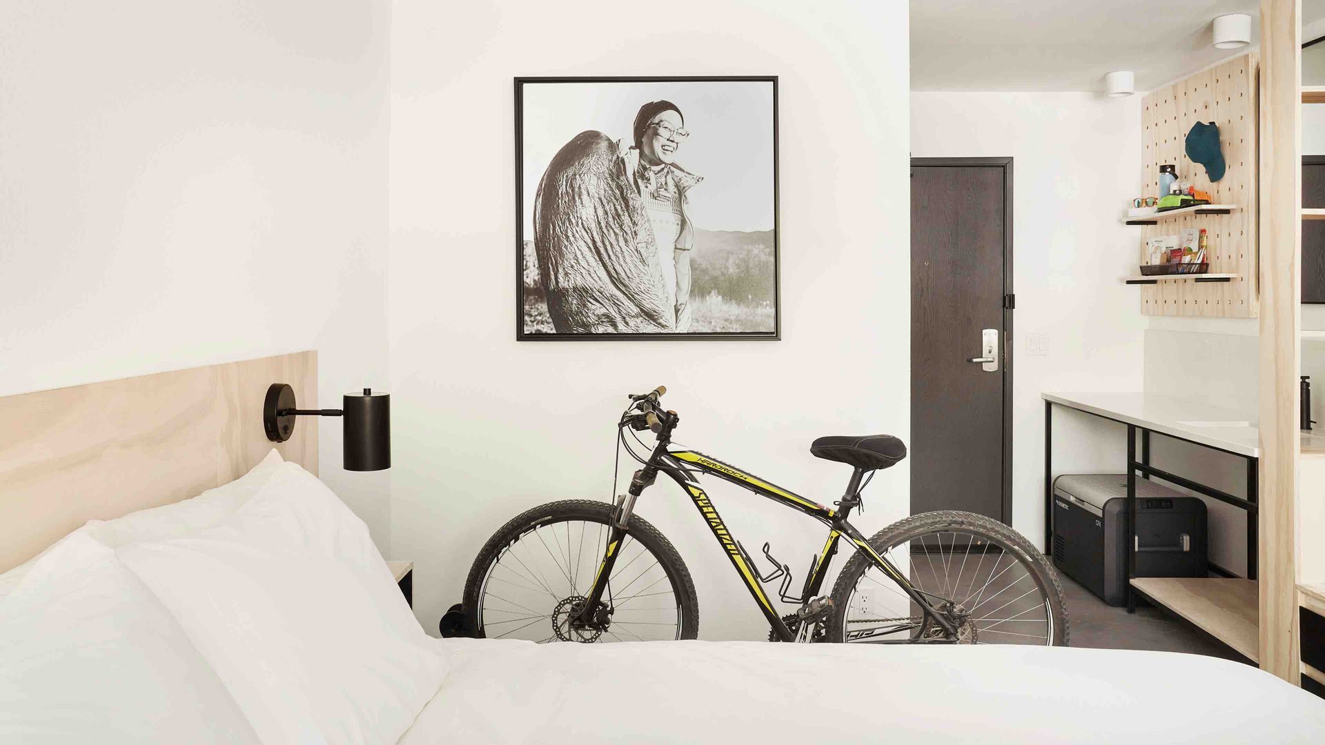 A bicycle is parked on a bed in a hotel room.