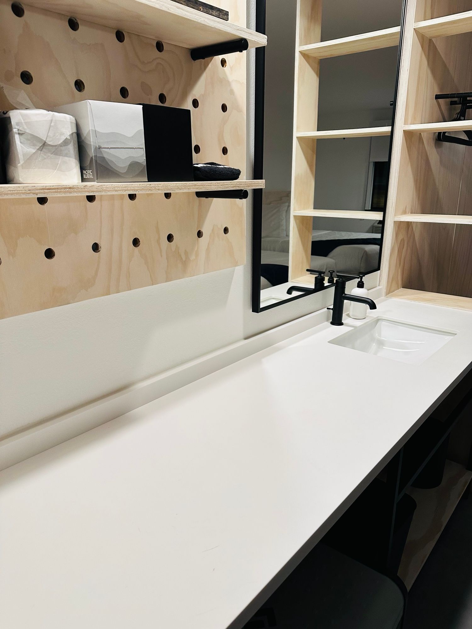 A bathroom with a sink , mirror and shelves.