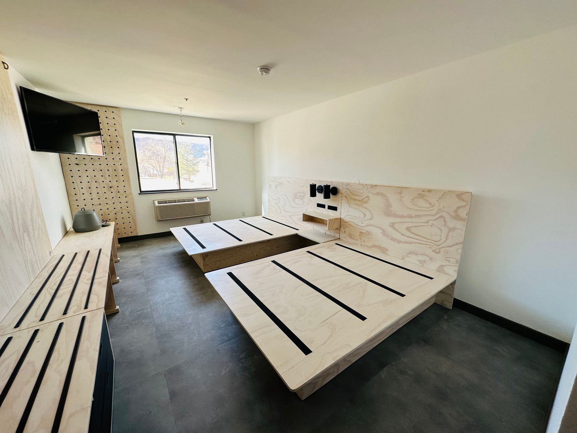 A hotel room with two beds and a television.