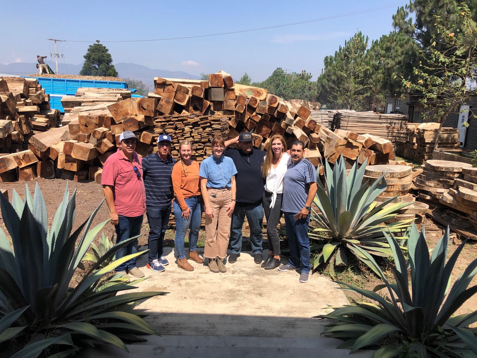 A group of people are posing for a picture in front of a pile of logs.