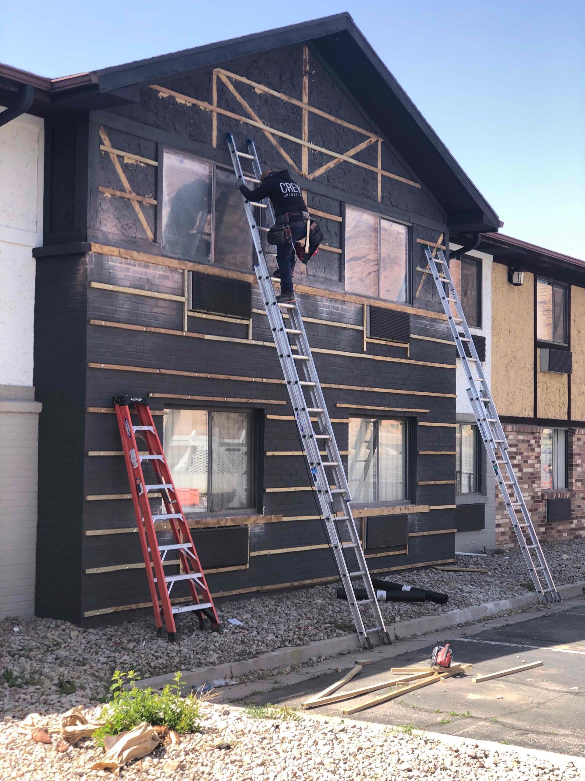 A man is standing on a ladder on the side of a building.