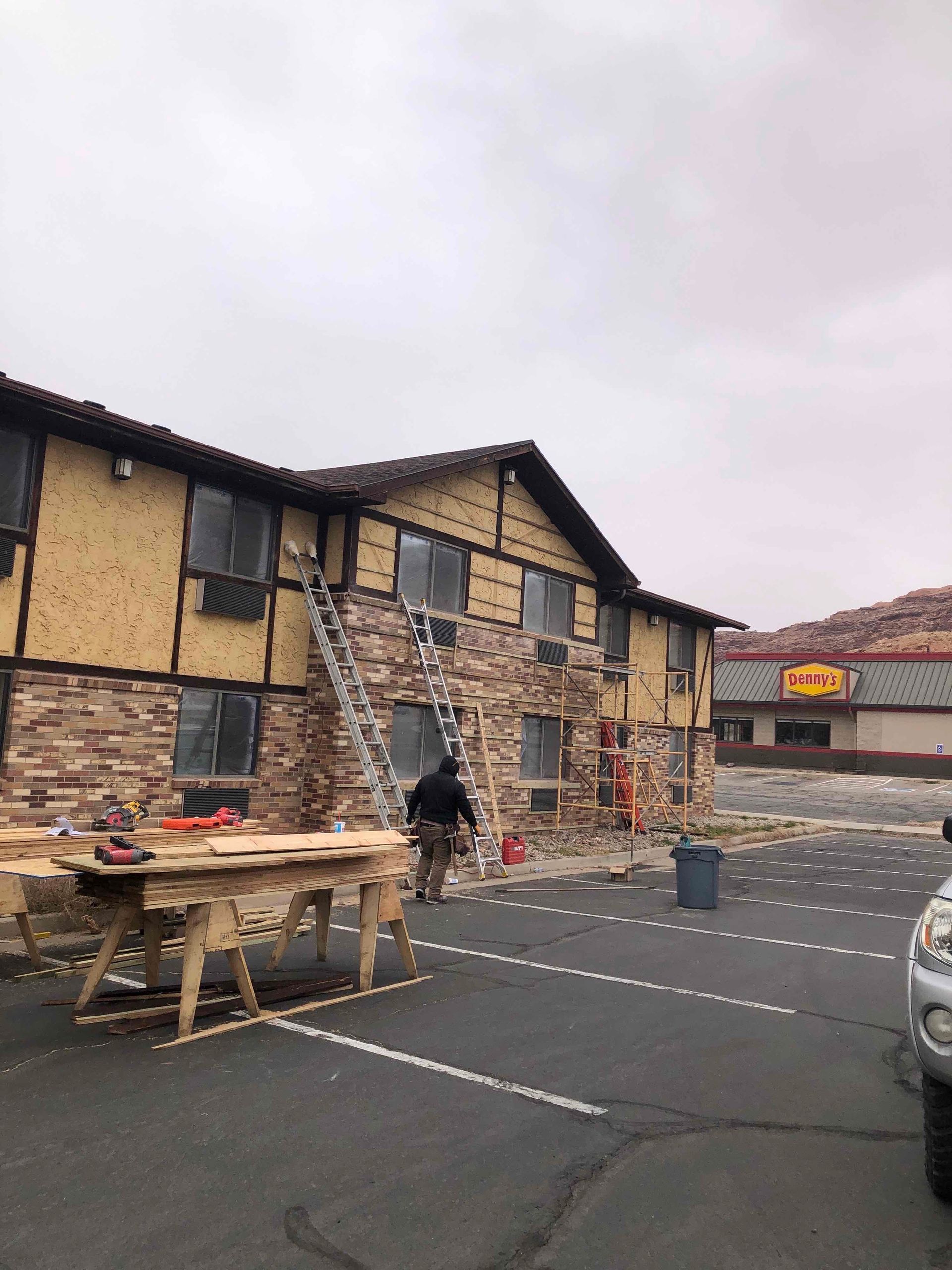 A man is standing in front of a building that is being remodeled.