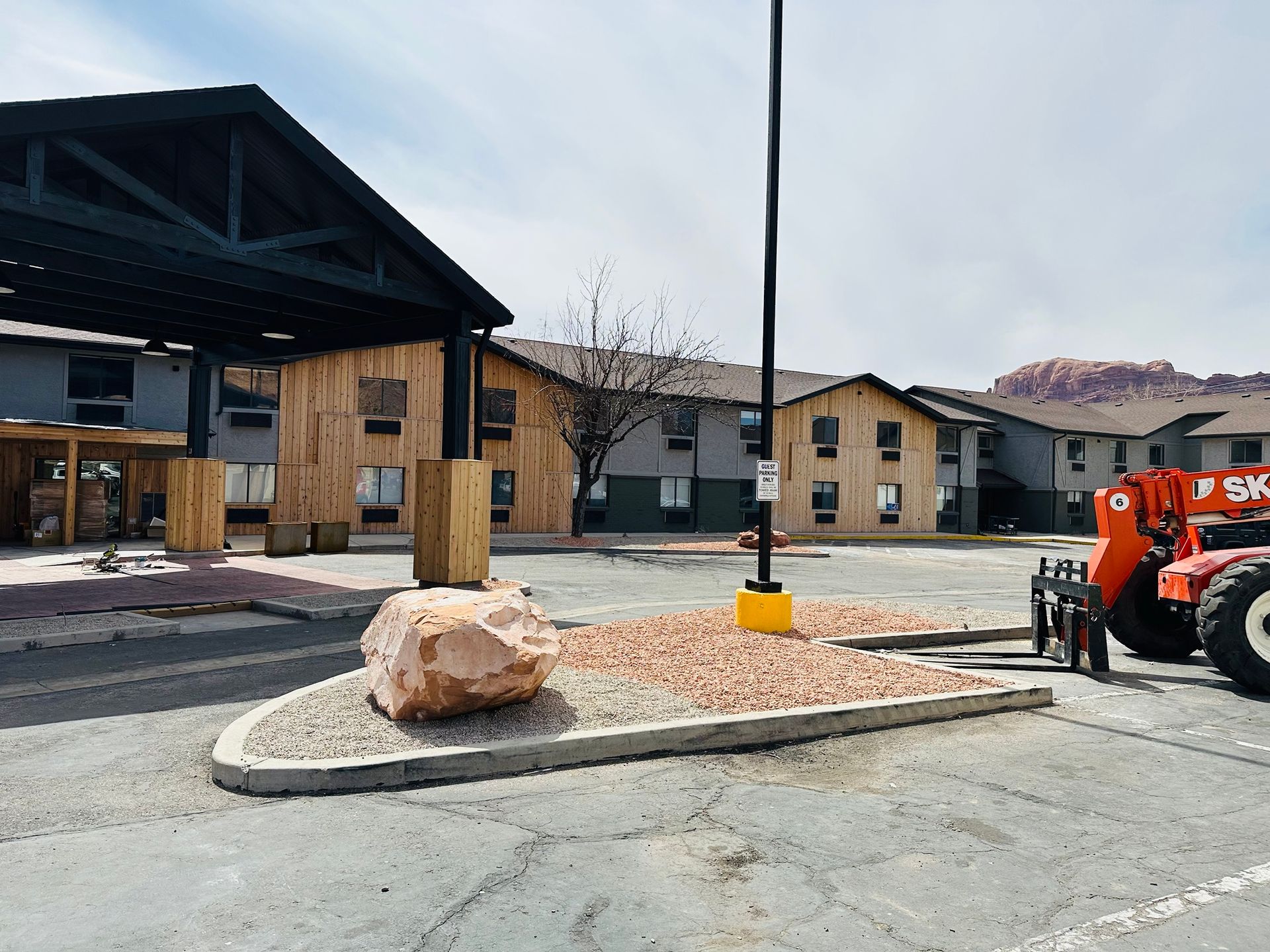 An orange forklift is parked in front of a hotel