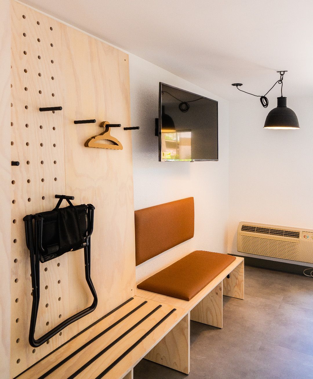 A room with a bench and a tv on the wall