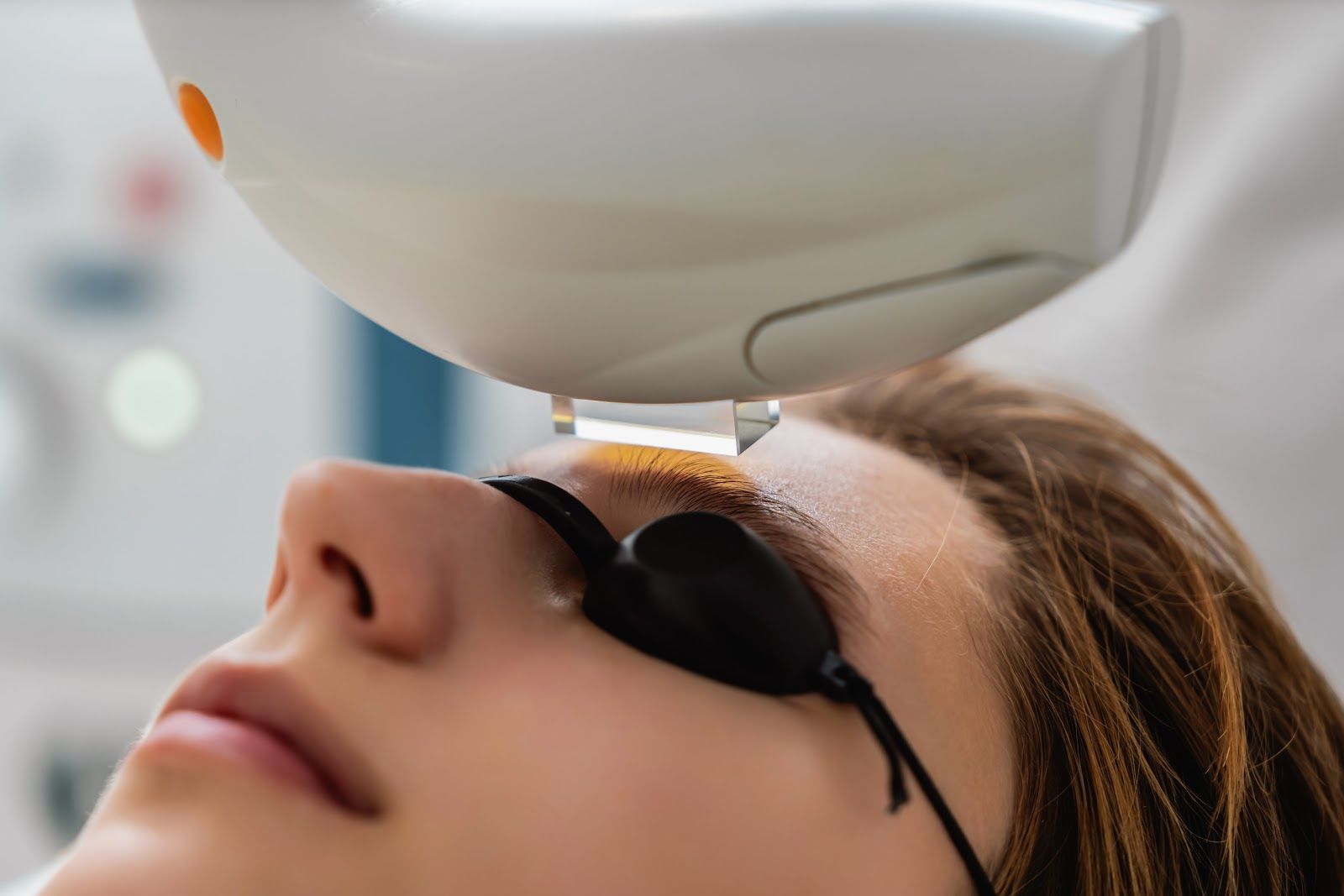 Person wearing protective eye shields during a light-based facial treatment