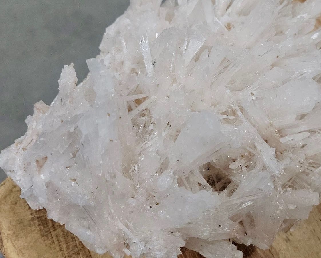 White, crystalline mineral formation with a fibrous texture and small dark specks.