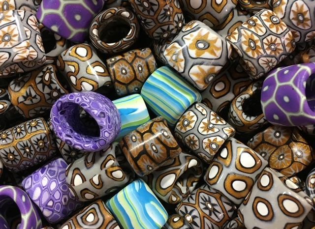 Pile of polymer clay beads with patterned designs in various colors.