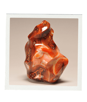 Polished orange and white agate gemstone with dark banding.