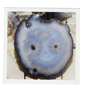 Cross-section of an agate stone, showcasing concentric gray, blue, and black bands.