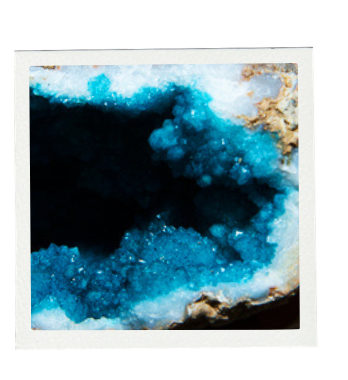 Blue geode crystal formation, black center, white and tan surrounding.