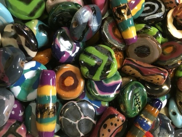 Pile of colorful, hand-painted ceramic beads in various shapes and patterns.