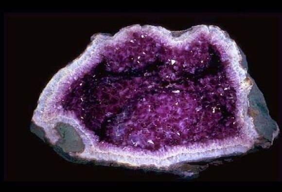 Amethyst geode, cavity lined with sparkling purple crystals. Gray and white outer rock.