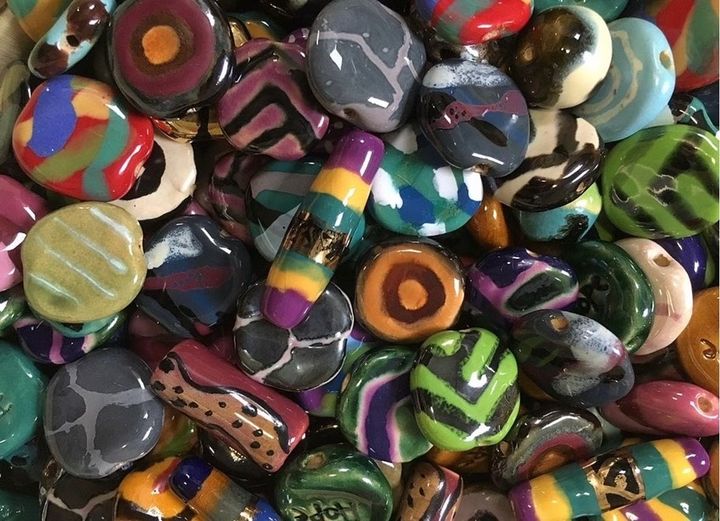 Pile of colorful glass beads with various patterns, including stripes, swirls, and spots.