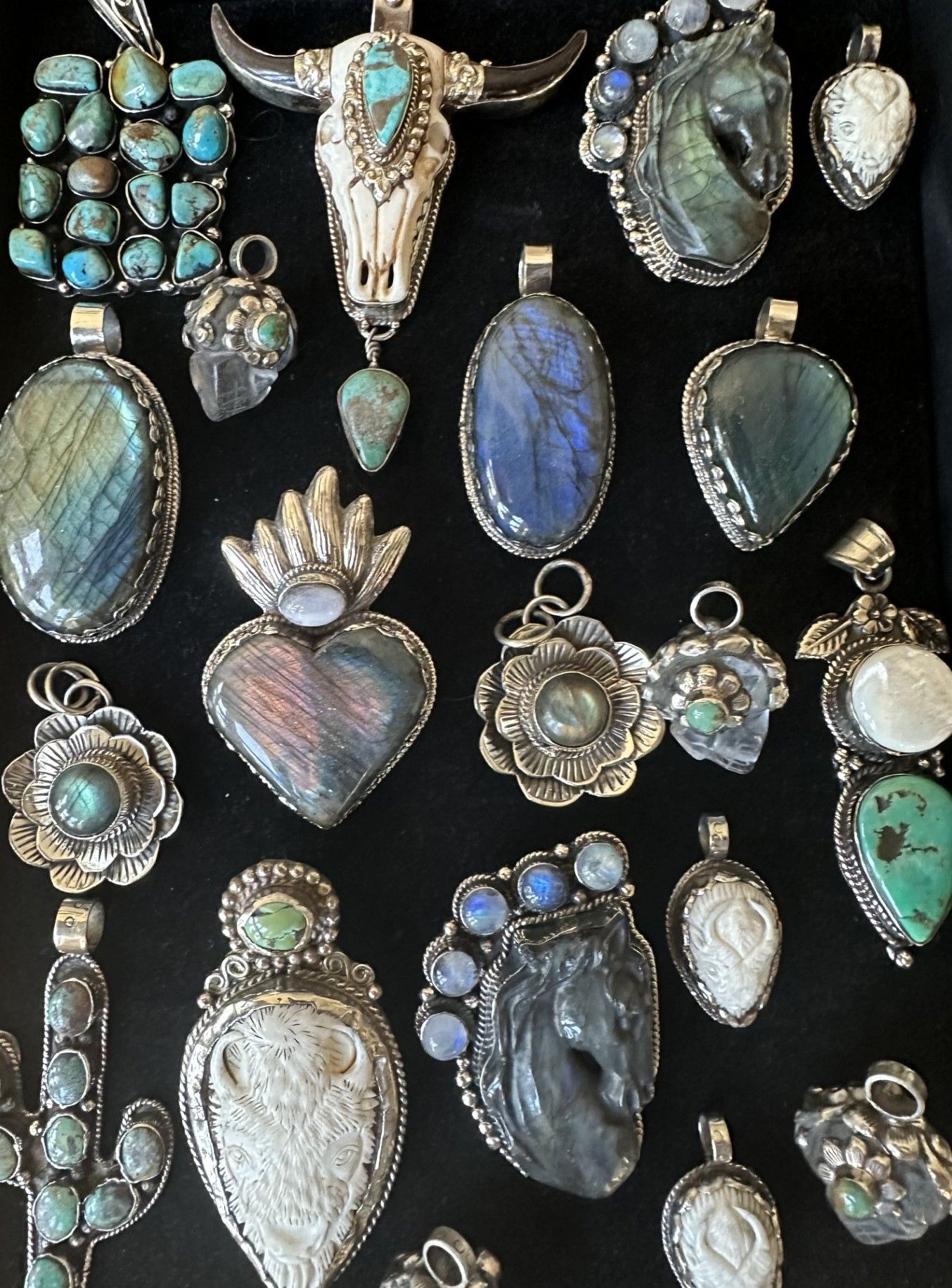 Collection of silver pendants with turquoise and labradorite stones displayed on a black background.