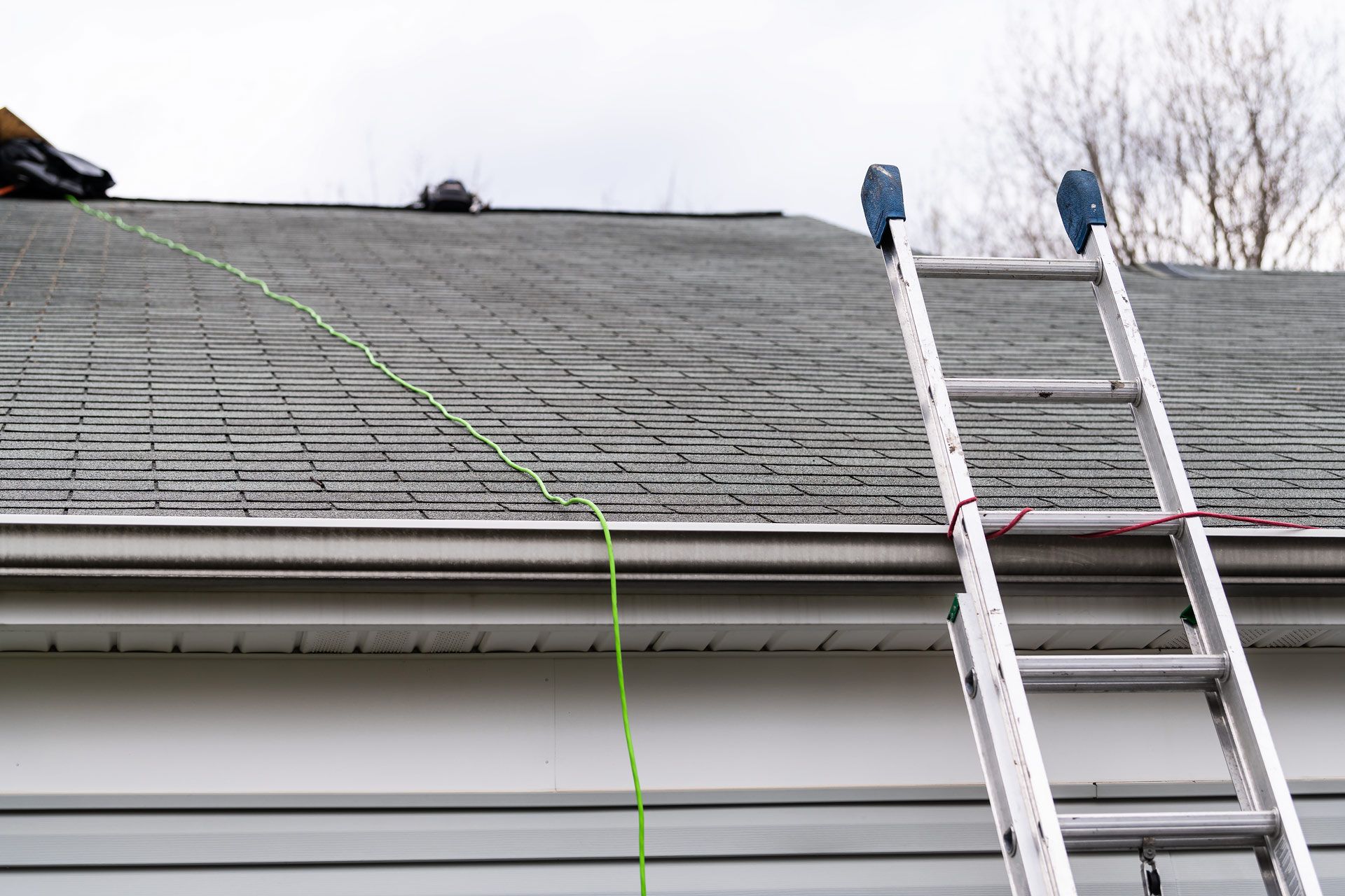 Ladder against a house with asphalt shingles for residential roofing inspection