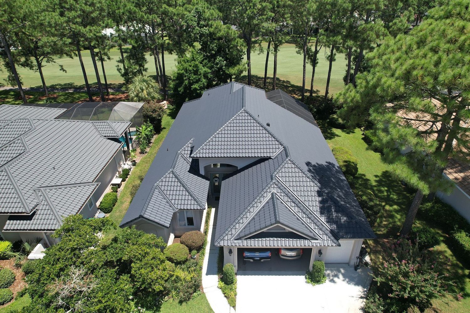 Aerial view of a gray-roofed house surrounded by trees and greenery