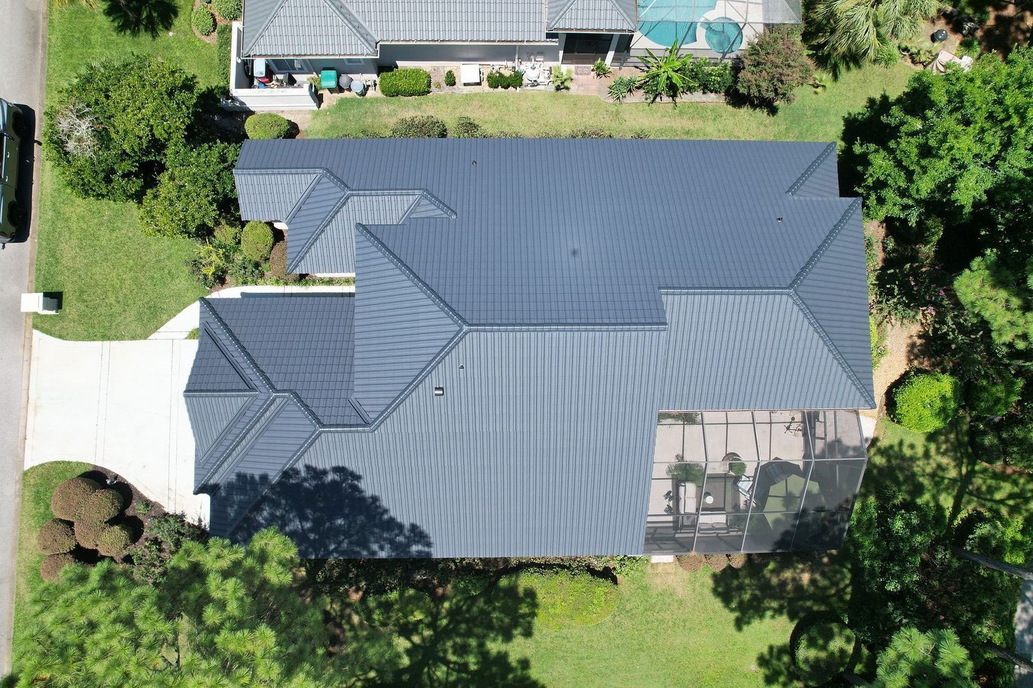 Aerial view of a gray-roofed house surrounded by trees and a driveway