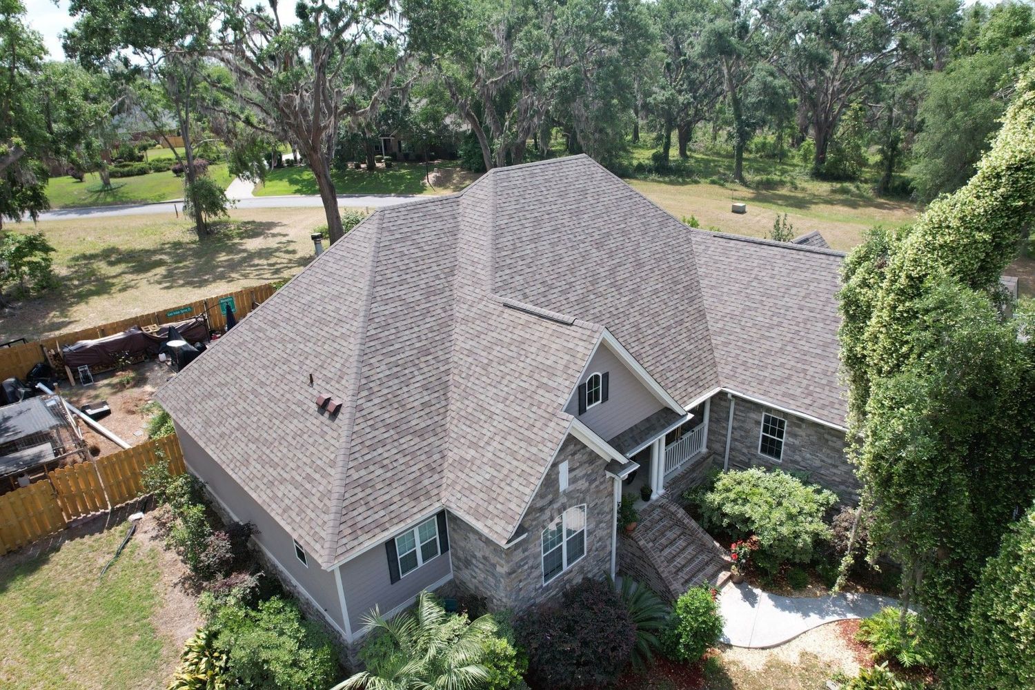 Aerial view of a gray-roofed house surrounded by trees and landscaping