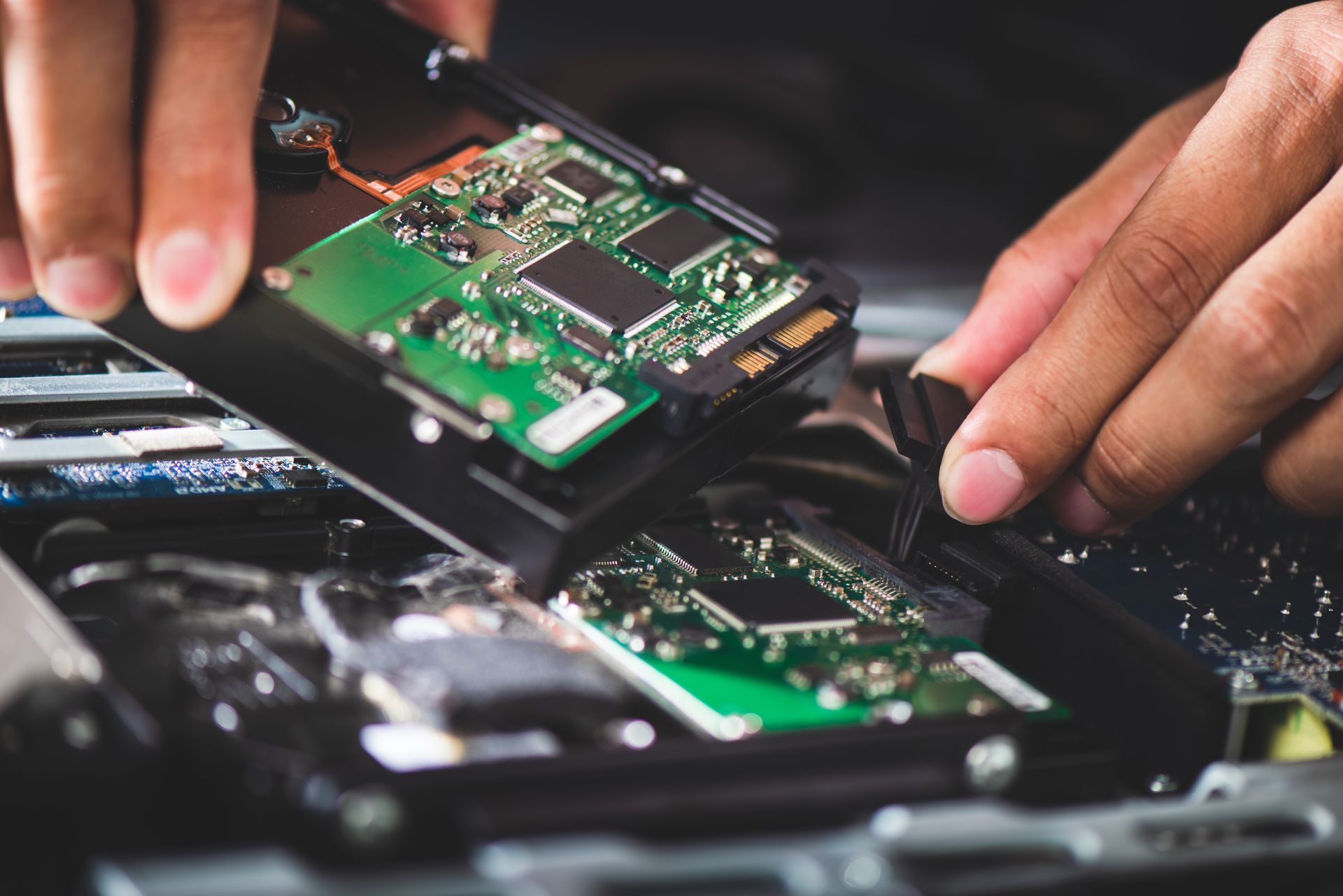Hands installing a green circuit board into an open electronic device