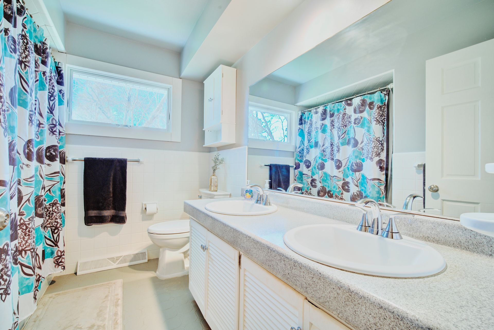 A bathroom with two sinks , a toilet , and a shower curtain.