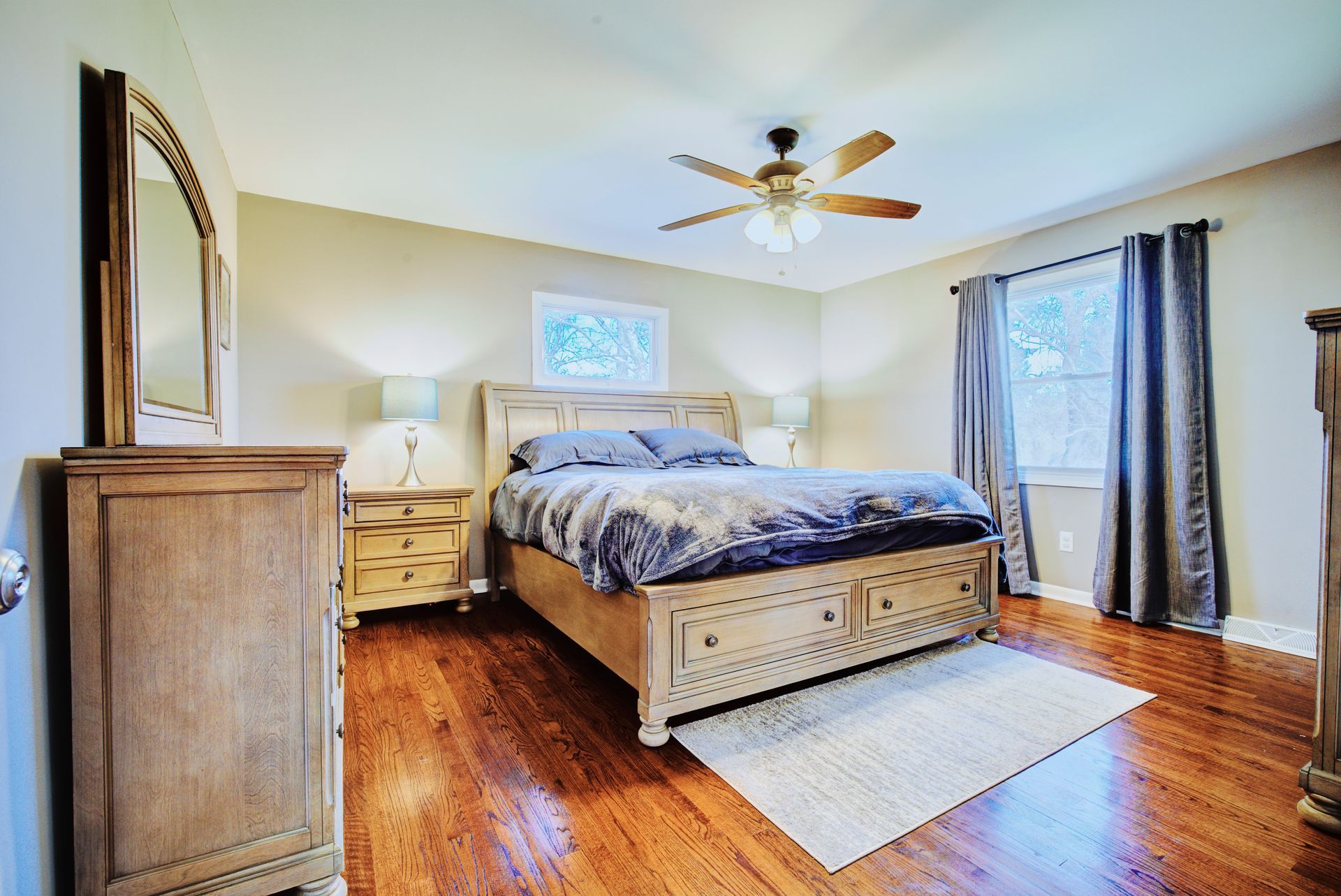 A bedroom with a bed , dresser , mirror and ceiling fan.