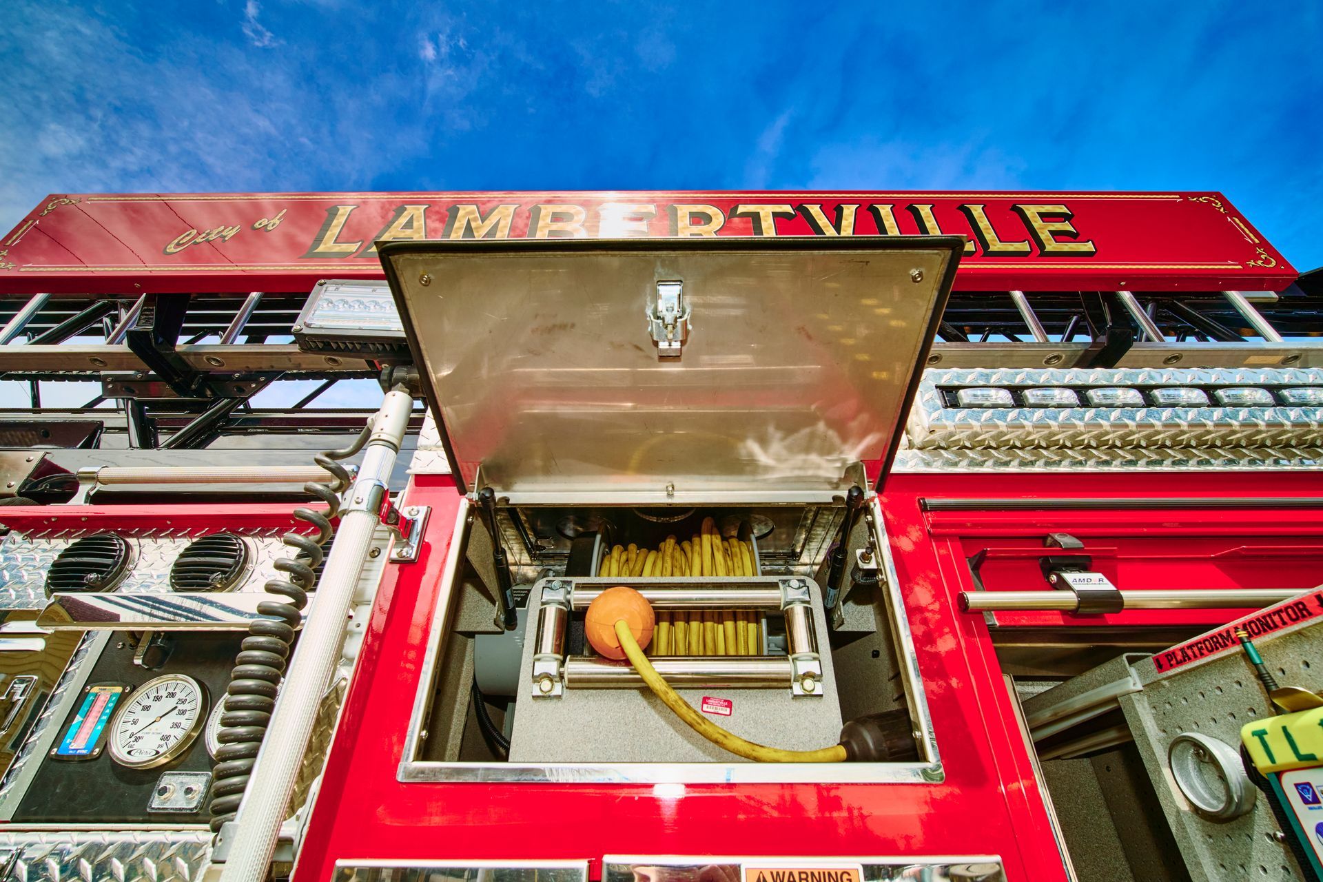 Red fire truck front with open compartment, hose and equipment, labeled “LAMBERTVILLE” on top.