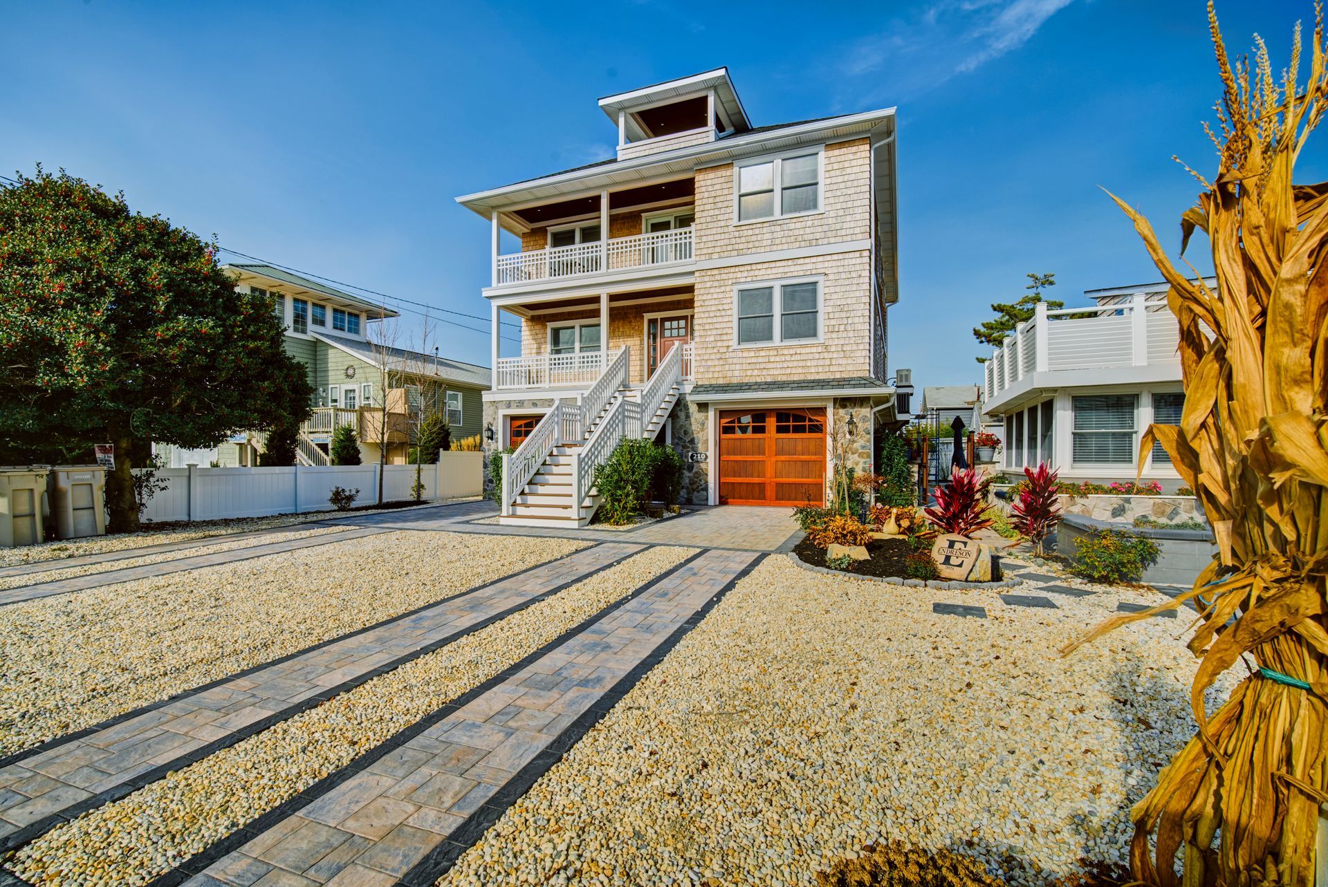 Three-story beach house with a deck and garage; beige exterior and stone accents.