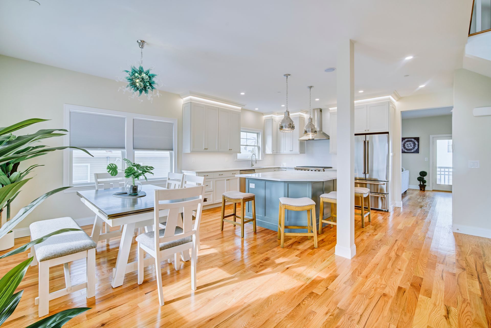 Spacious kitchen with wood floors, island, dining table, and large windows. Bright, airy, and modern.