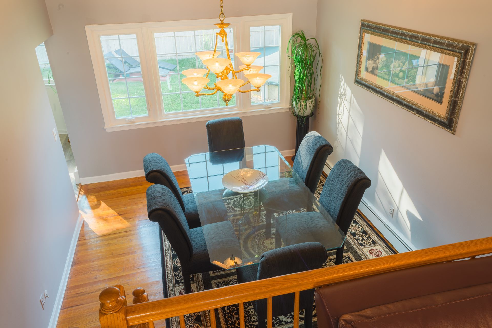 Dining room with glass table, black chairs, chandelier, and a large window.