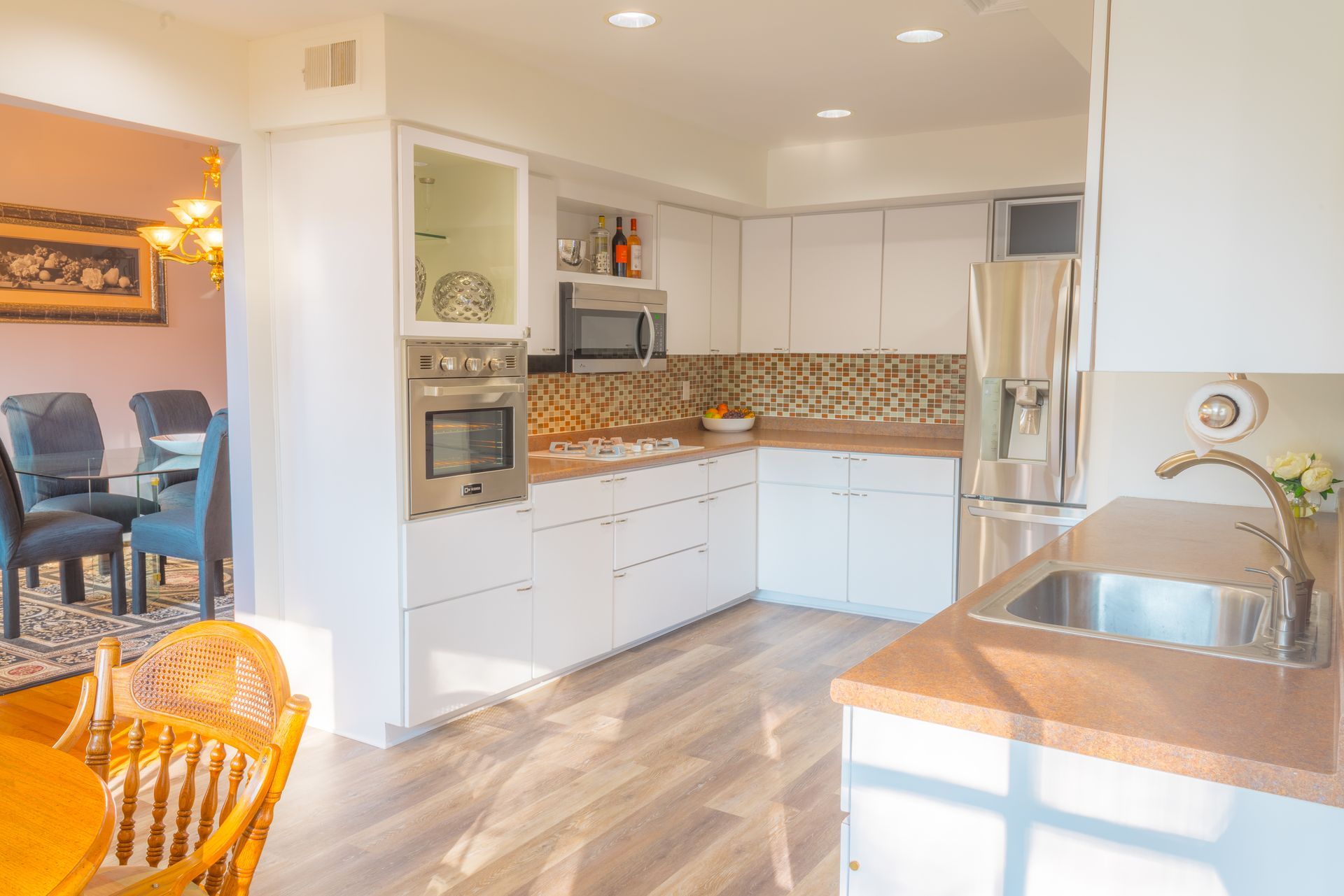 White kitchen with wooden countertops, stainless steel appliances, and adjacent dining area.