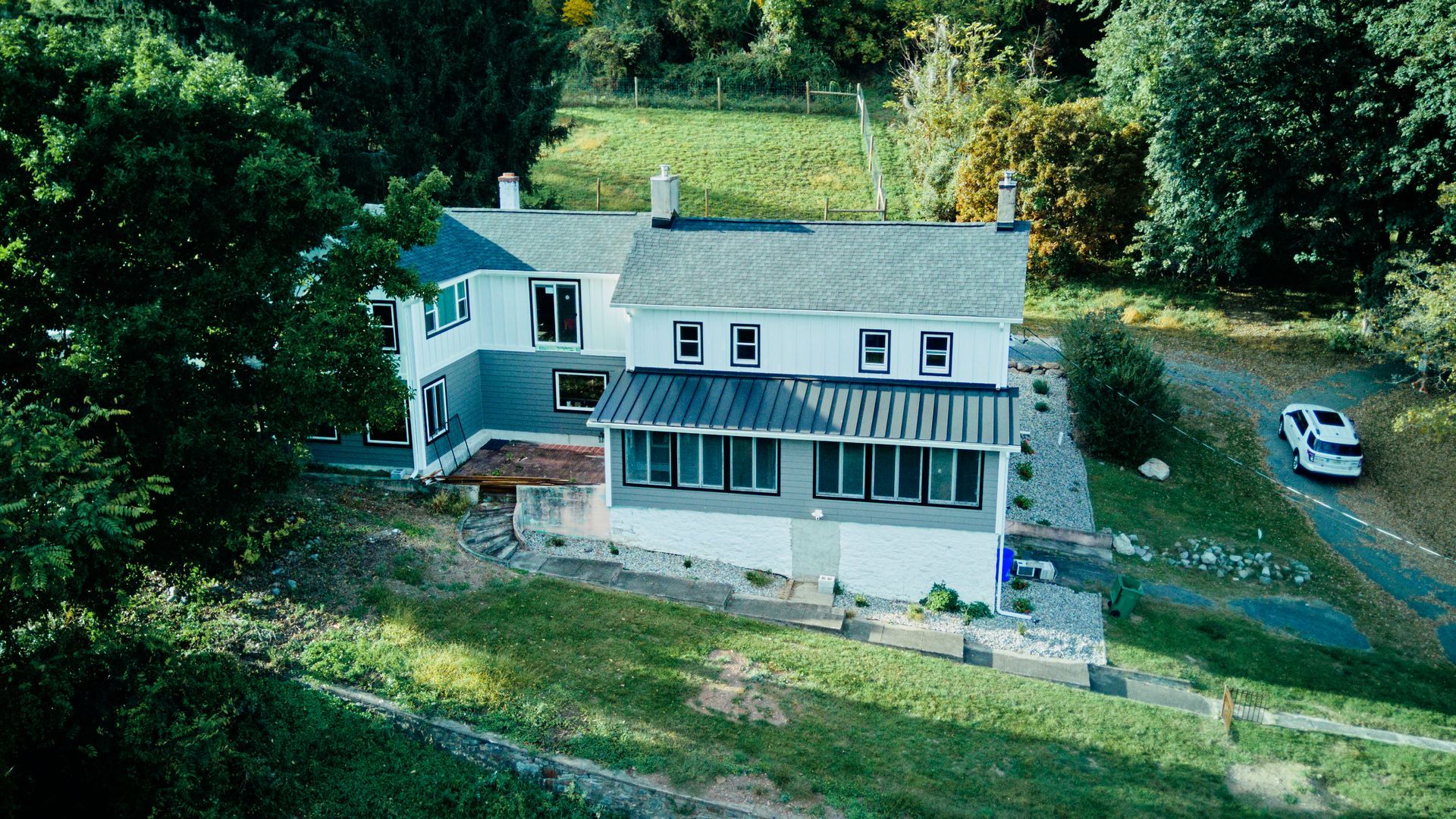 An aerial view of a large white house surrounded by trees and grass.