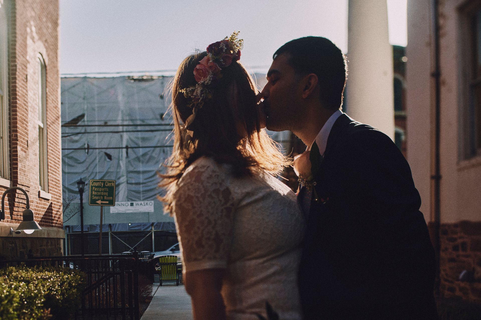 A bride and groom are kissing in front of a building.