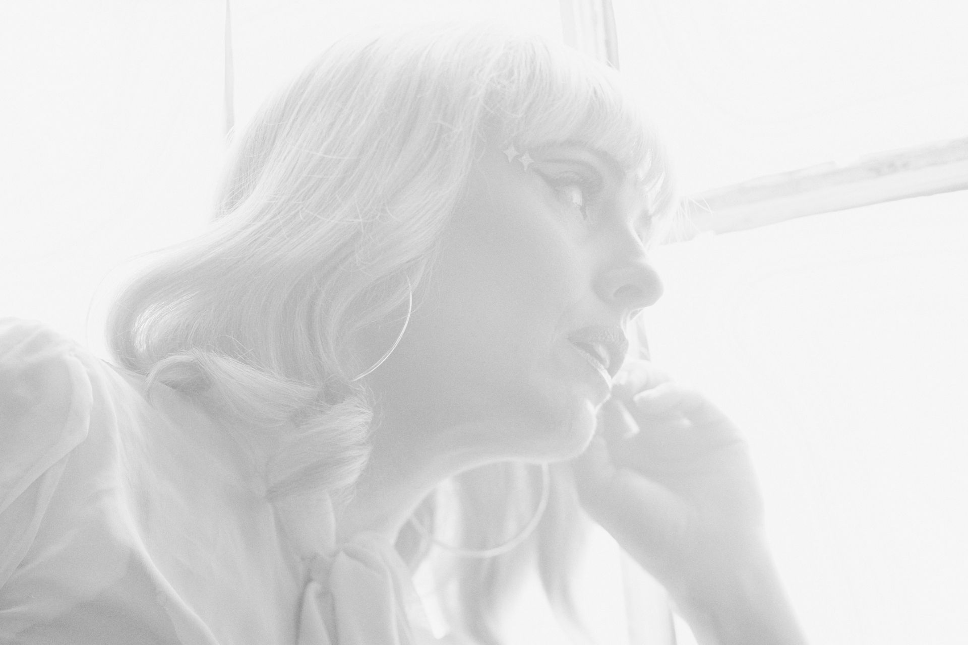A black and white photo of a woman looking out a window.