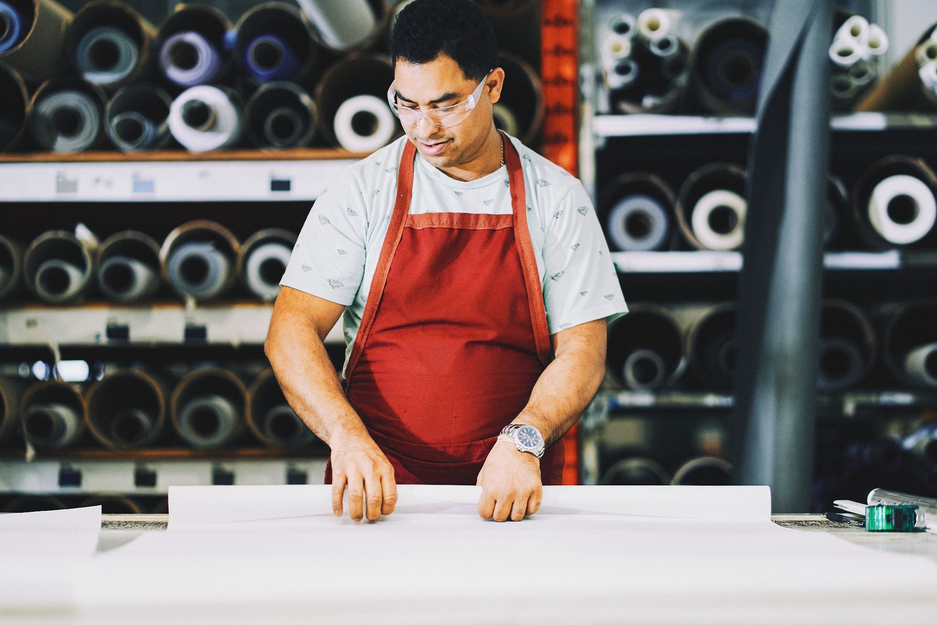 A man in an apron is standing at a table in a factory.