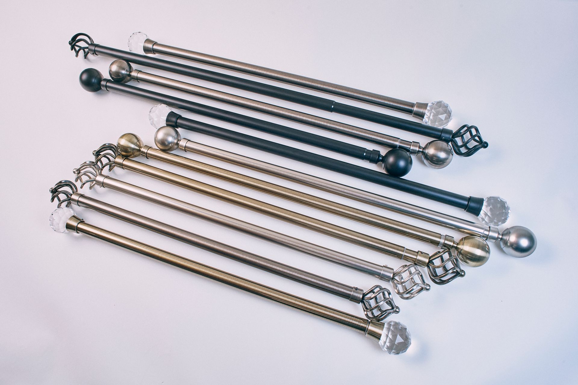 A bunch of curtain poles are stacked on top of each other on a white surface.