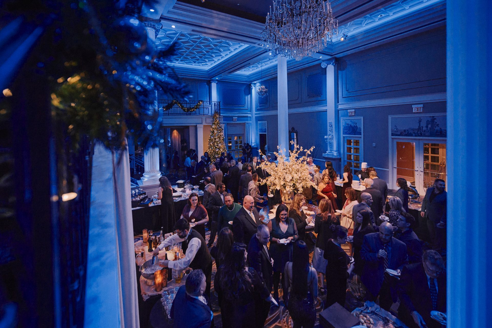 A large group of people are standing in a large room with blue lights.