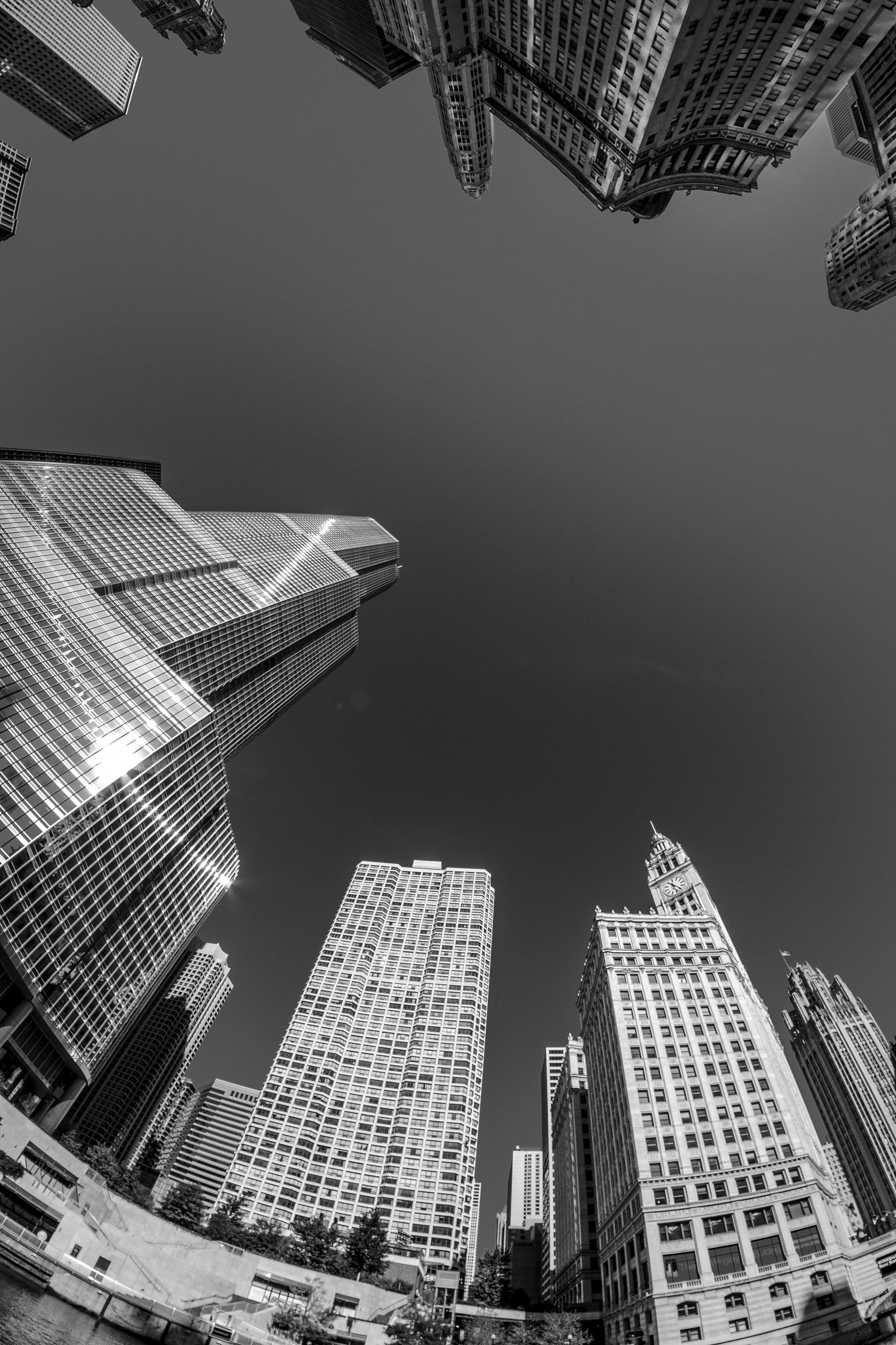 Low-angle shot of tall skyscrapers in a city, looking up at the sky. Black and white.