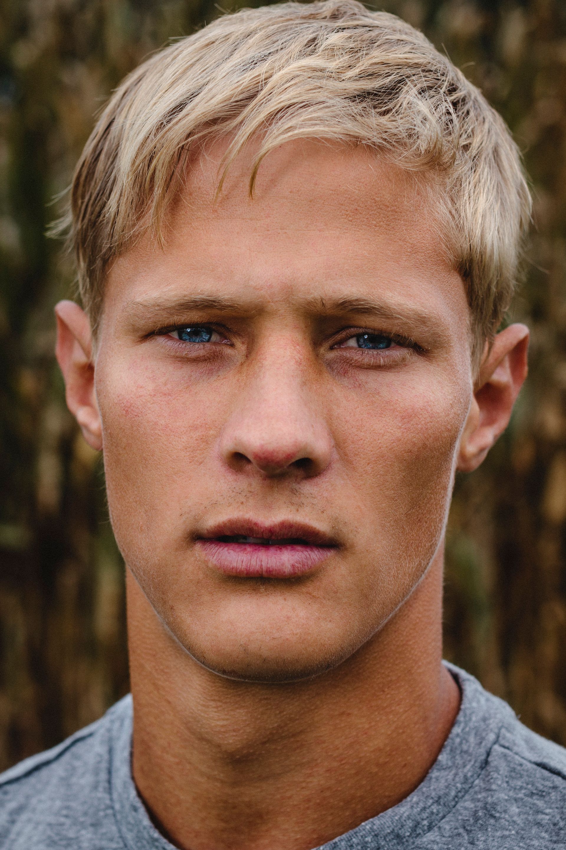 A close up of a man 's face with blonde hair and blue eyes.