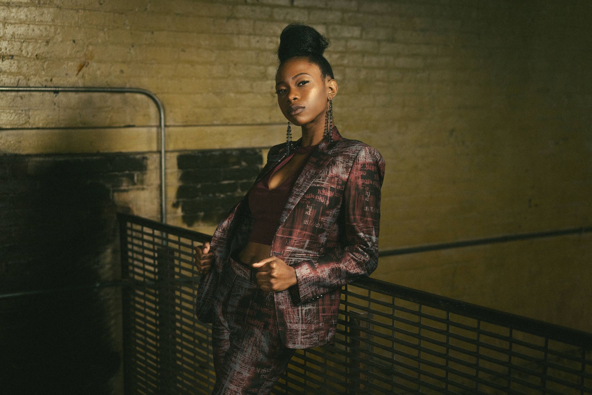 A woman in a suit is standing next to a fence.