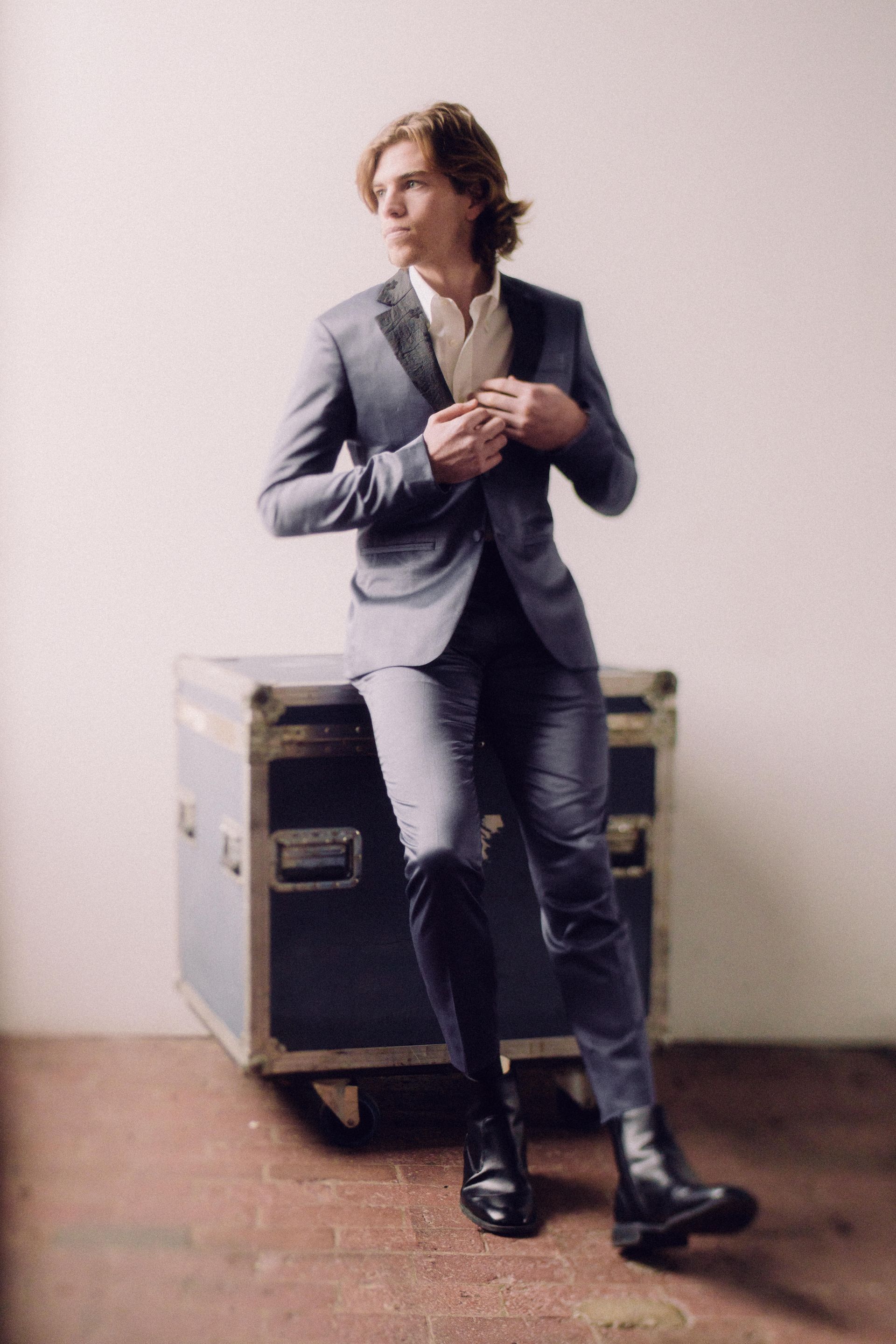 A man in a suit is sitting on a suitcase.