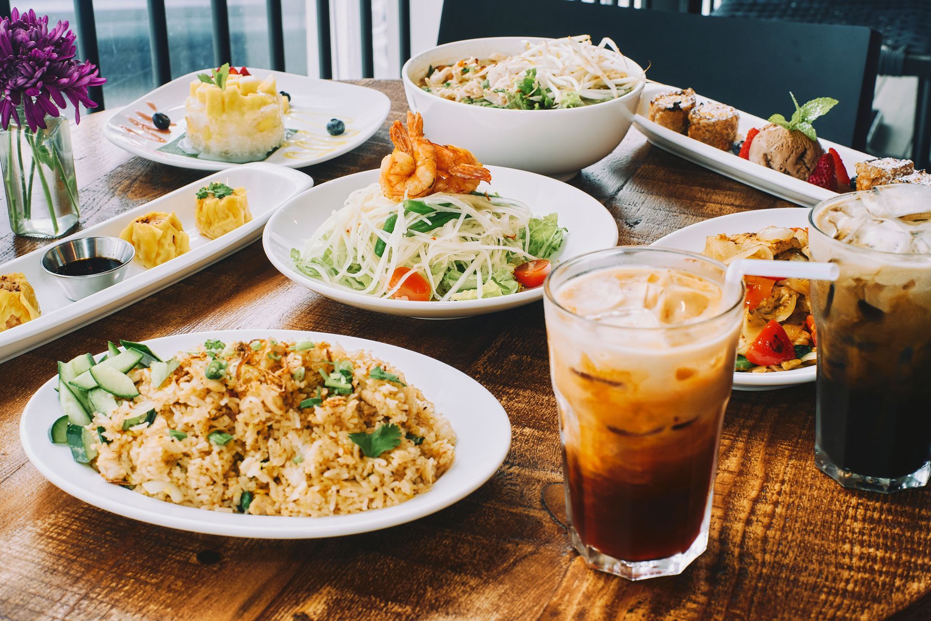 Table of Thai food: noodles, rice, shrimp, drinks, and desserts.