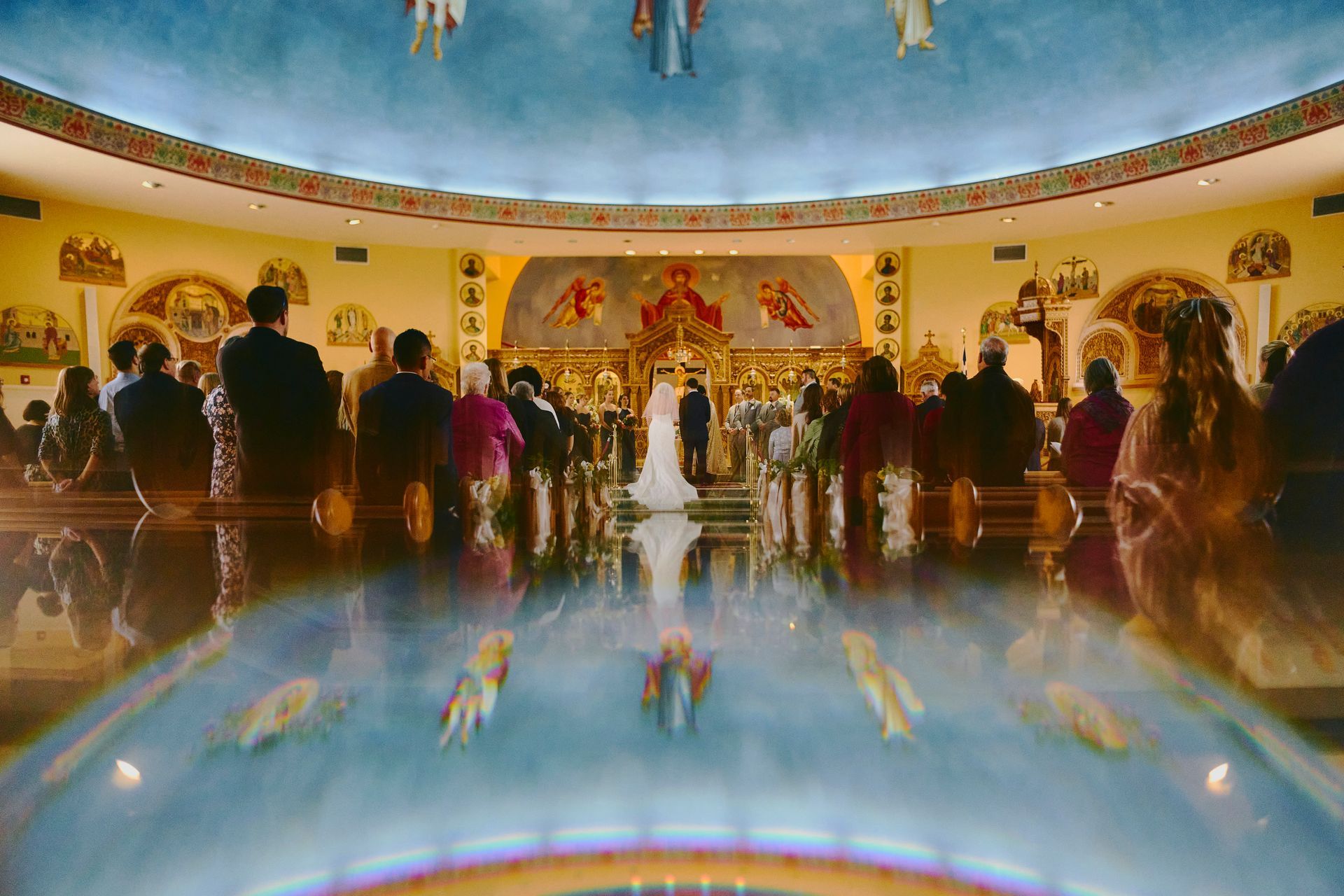 A group of people are standing in a church watching a wedding ceremony.