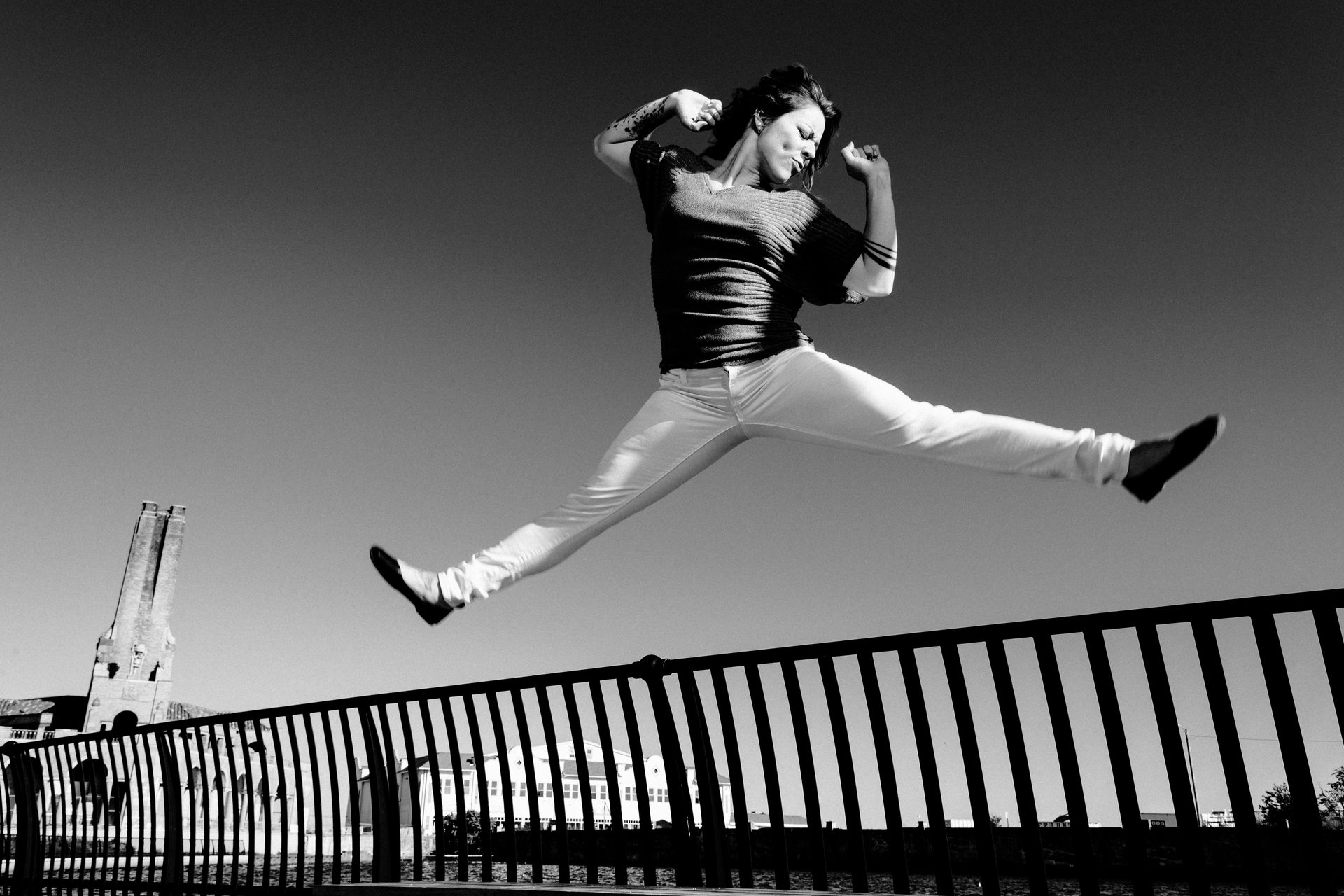 A black and white photo of a person jumping over a fence